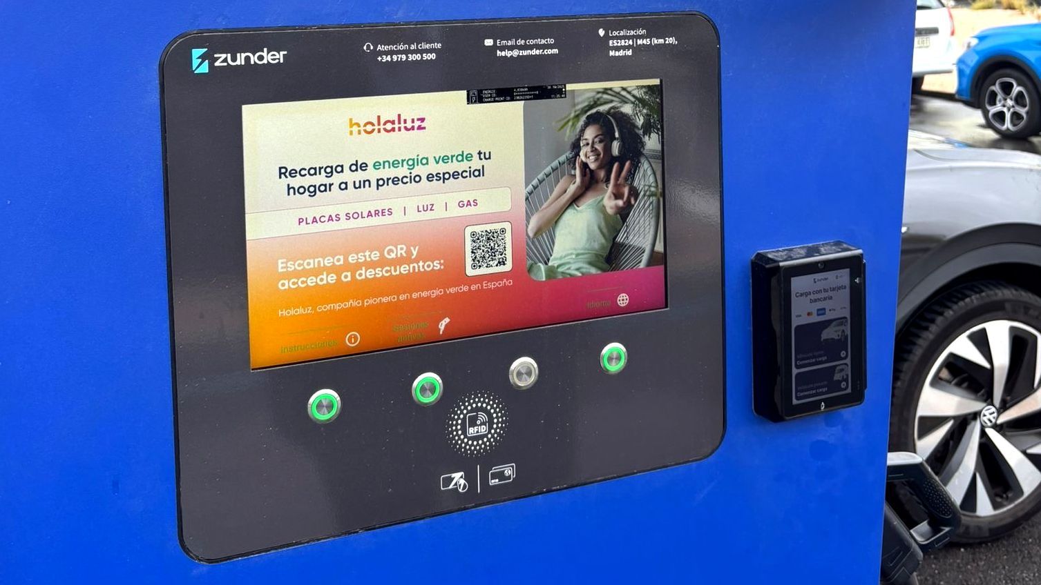 Punto de recarga para vehículo eléctrico con pantalla informativa de Zunder y promoción de Holaluz